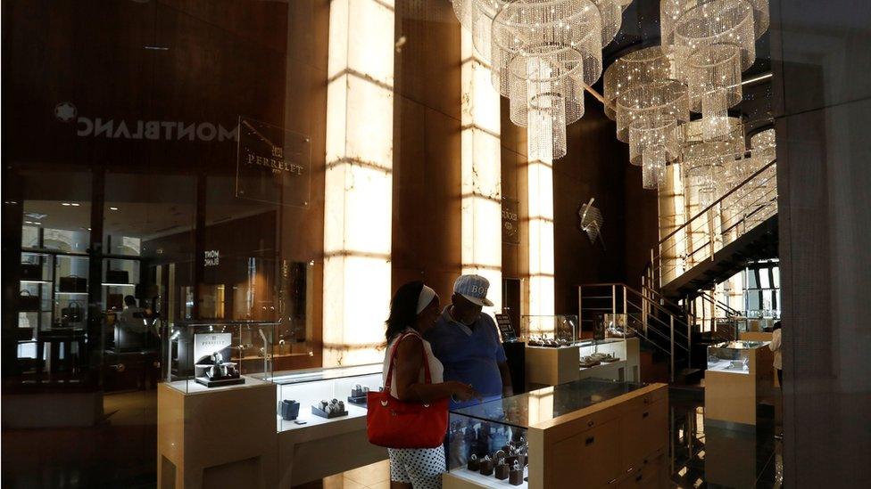 people checking out the goods at a Montblanc store, under chandaliers