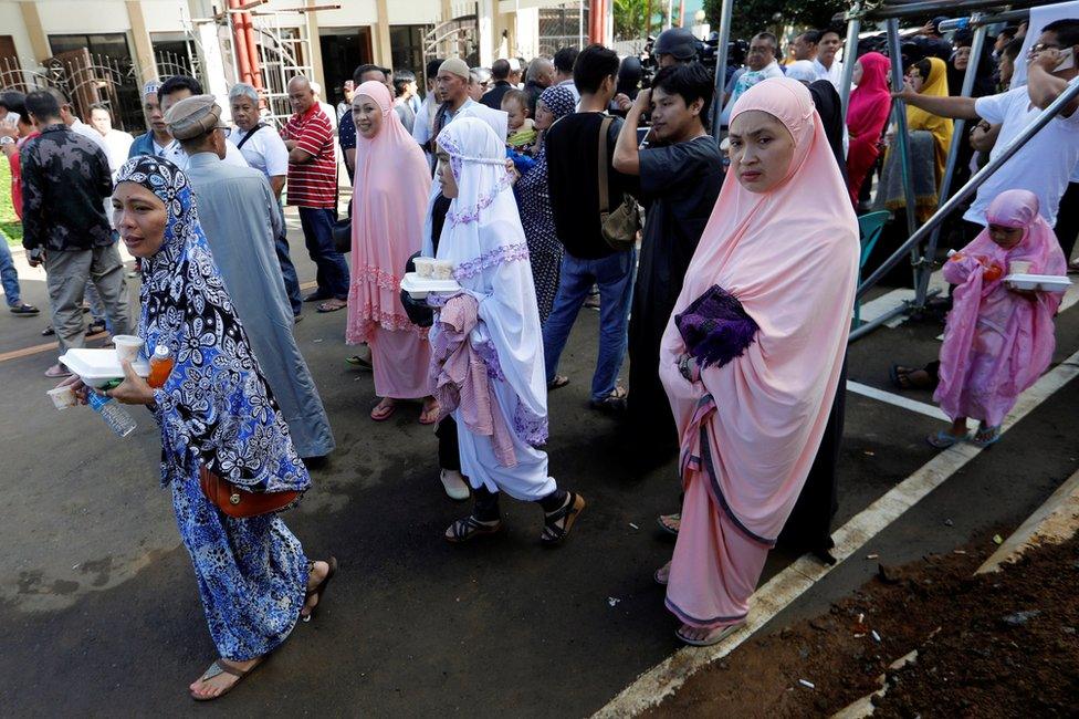 Muslim women walk after praying during Eid al-Fitr at a mosque inside the city hall compound in Marawi City, Philippines, 25 June