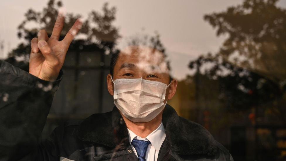 A hotel guard gestures while looking at the camera in Wuhan in China's central Hubei province