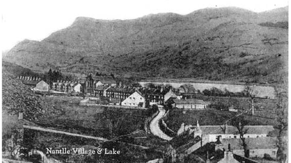 Hen lun o bentref Nantlle. Y talcen tŷ gwyn gyda'r holl ffenestri yng nghanol y llun yw'r Tŷ Nant newydd