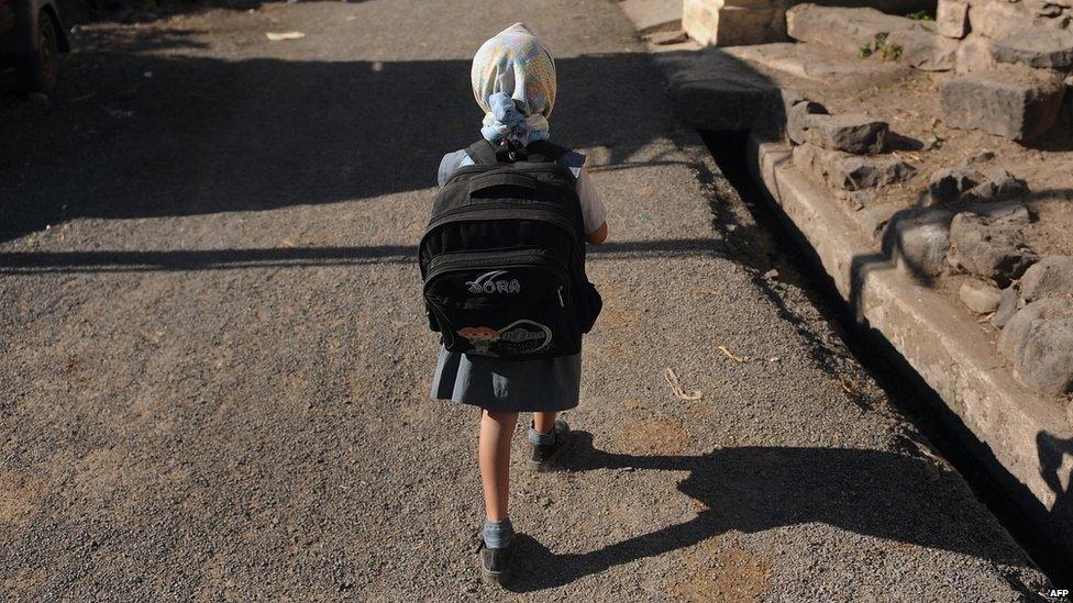 An Indian child wearing a backpack walks to school