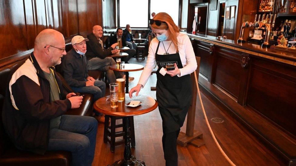 A waitress wears a mask as she works in the pub The Grill in Union Street