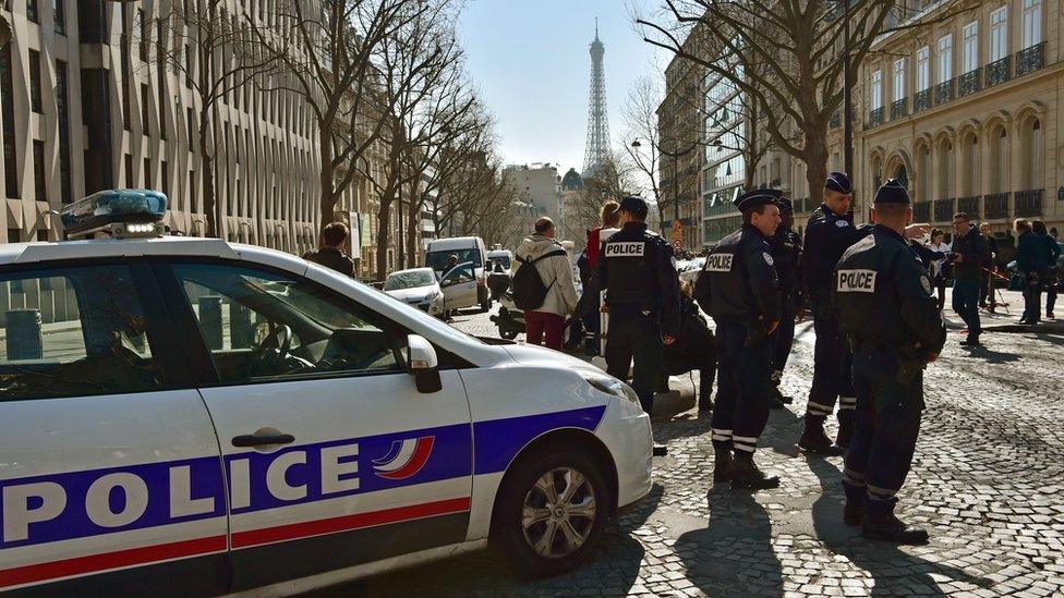 French police stand near a police car outside the IMF offices in Paris, with Eiffel tower in background, on March 16 2017