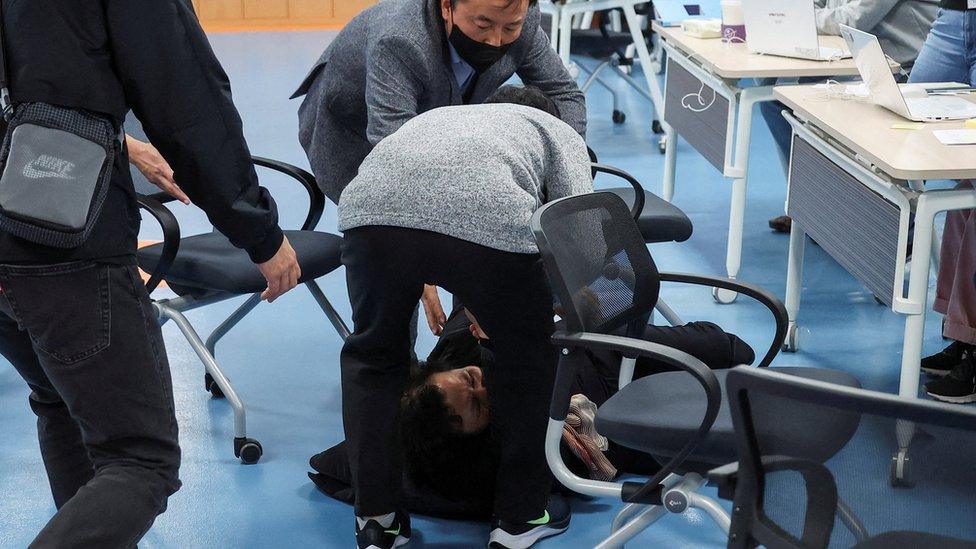 A parent of one of the crush victims falls to the community centre floor