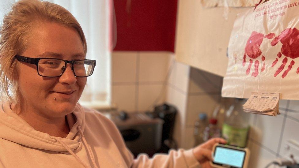 Nikita Harris holding a smart meter in her kitchen