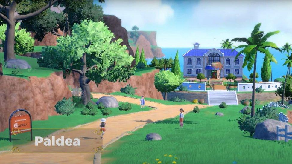 screengrab from footage of the pokemon violet and scarlet game showingnon playable characters walking aroudn in a landscape with trees, fields, a building next to a sea