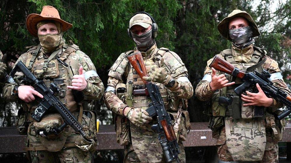 Three Wagner fighters holding guns pose for a photo