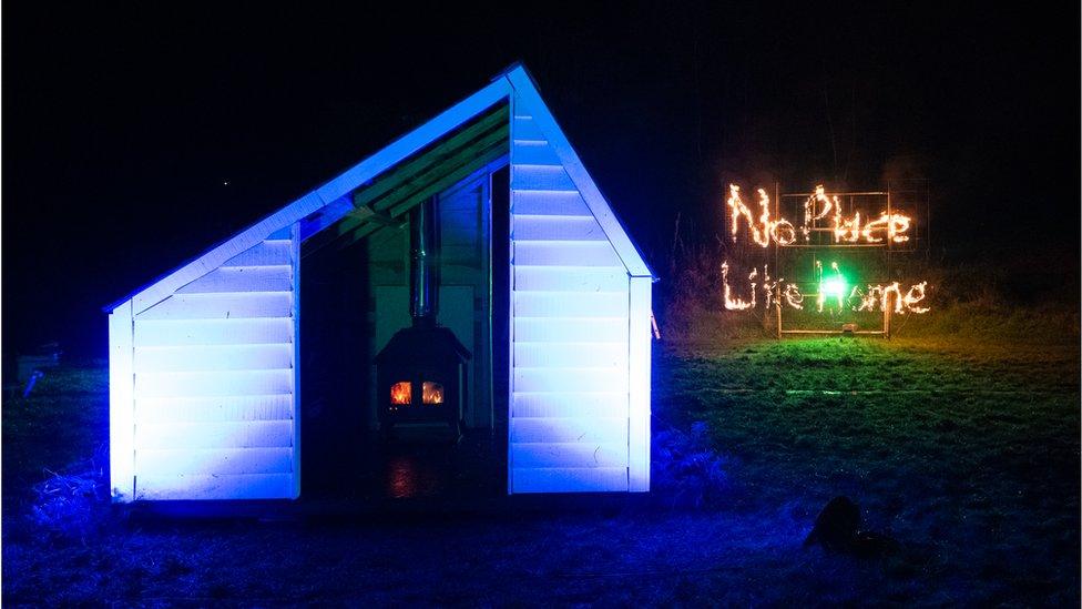 The finished house with an adjacent sign saying "no place like home"