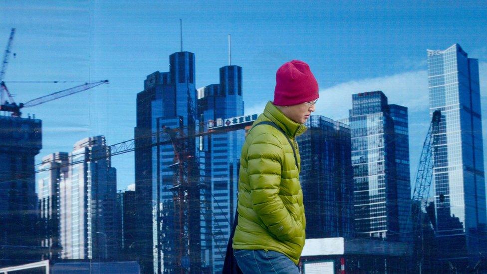 A man walks past a billboard in Beijing