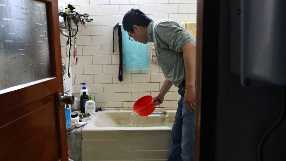 A man scoops water from a bathtub, where he stores water amid water rationing during an island-wide drought, in Hsinchu, Taiwan March 12, 2021.