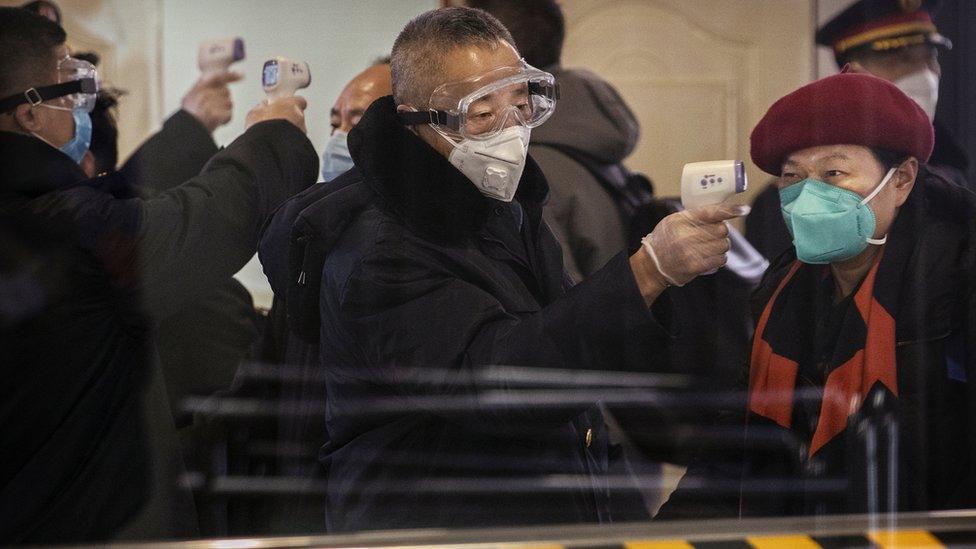 Passengers disembarked from bullet train from Wuhan are checked by health workers at a Beijing railway station