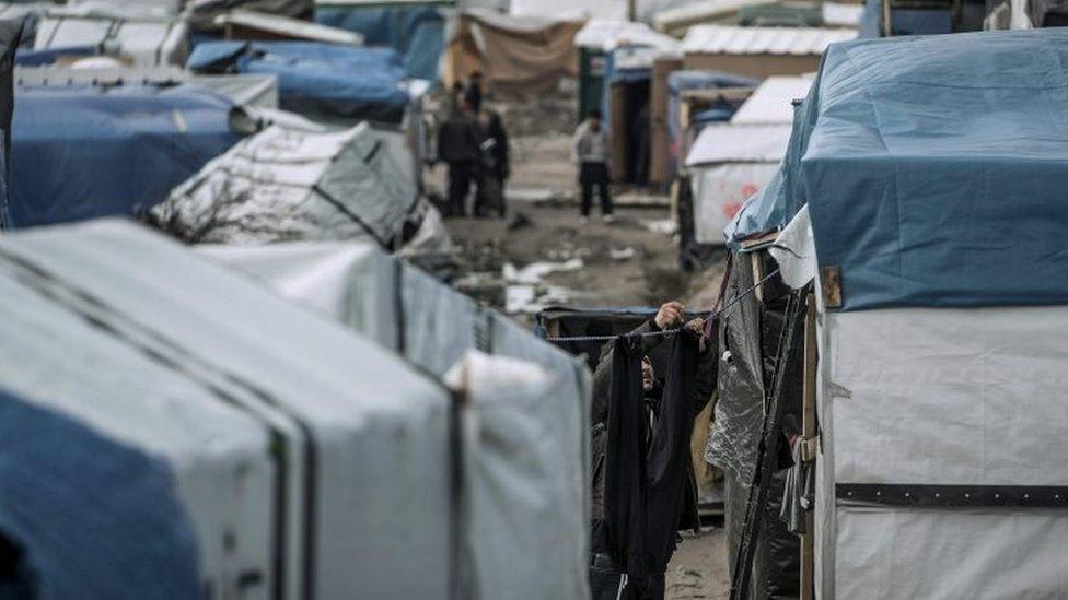 A migrant hangs laundry outside his tent in the "Jungle" (30 March 2016)