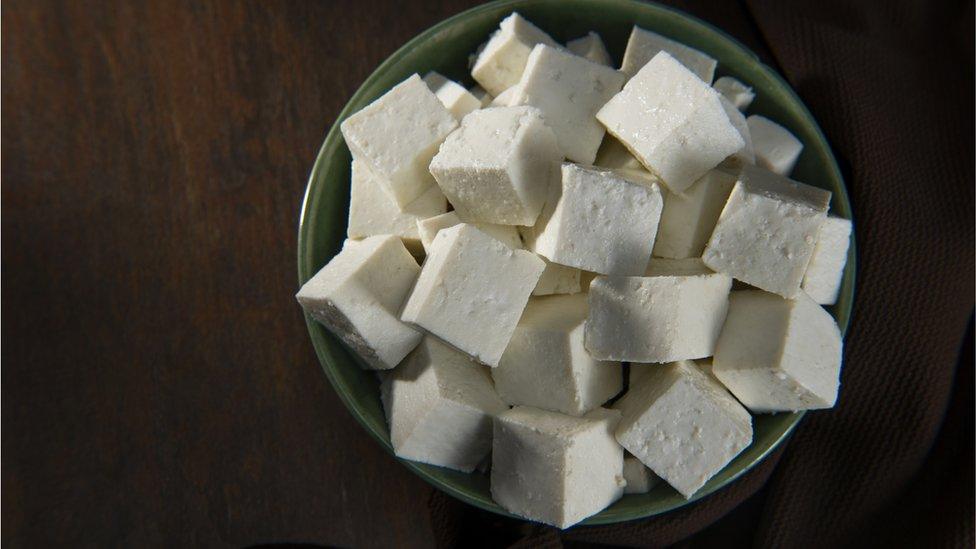 Diced Paneer or cottage cheese in a green bowl - stock photo