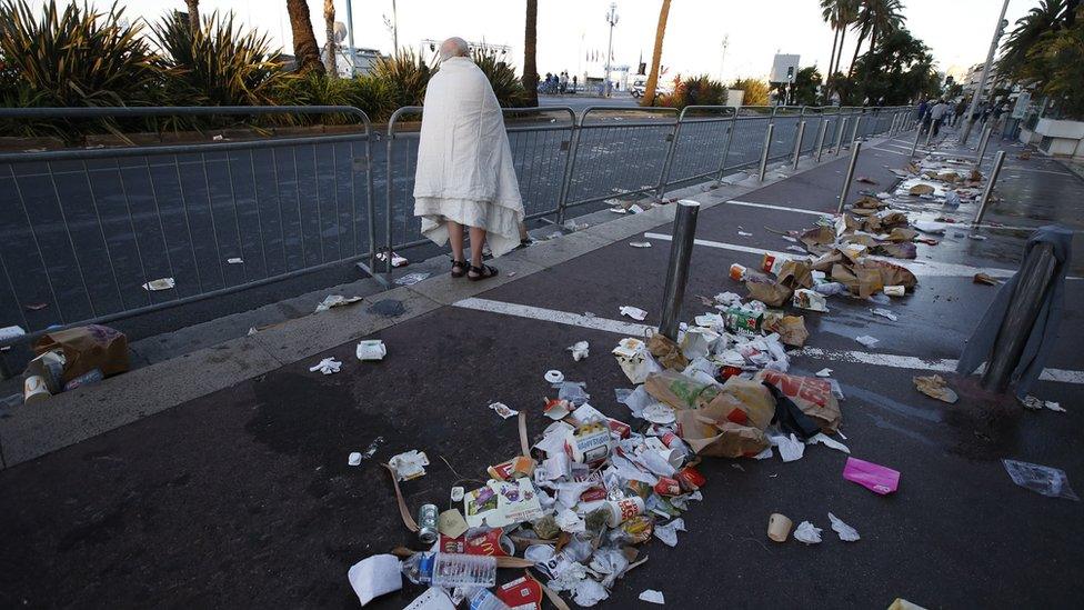 A man walks through debris on the street the day after a truck ran into a crowd