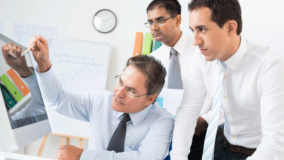 Business people gathered round a monitor