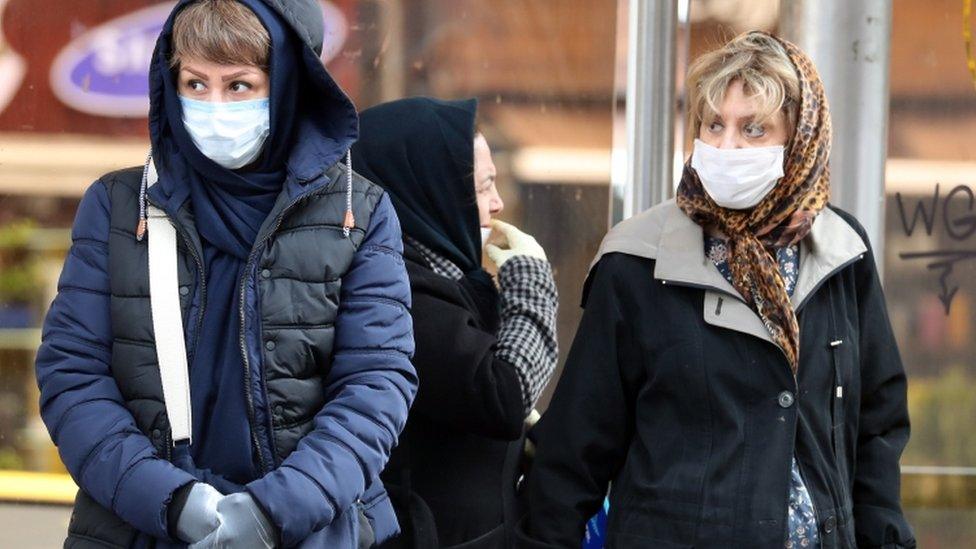 Iranians wearing face masks walk past in a street of Tehran, Iran, on 26 February 2020