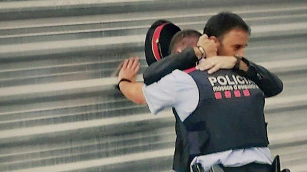 This photograph of a man hugging an apparently distressed Catalan policeman captured an emotional moment for a nation in crisis - what's the story behind it?