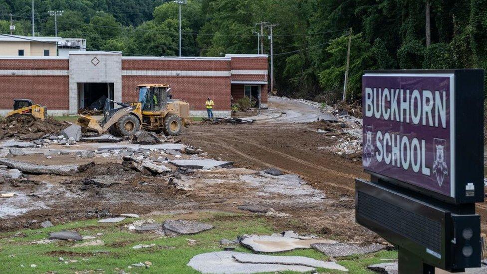 Image shows workers clearing debris in front of a school