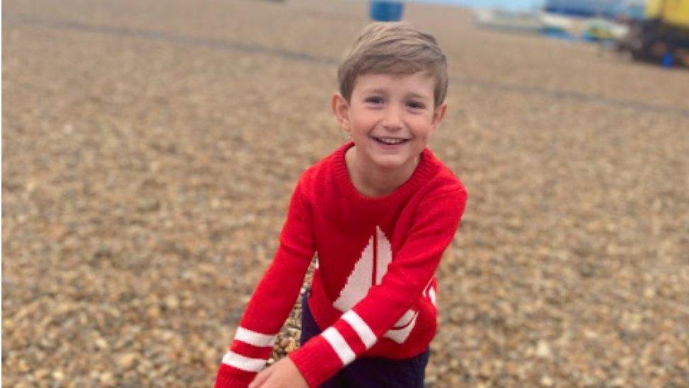 Benedict Blythe wearing a red jumper and playing on the beach.