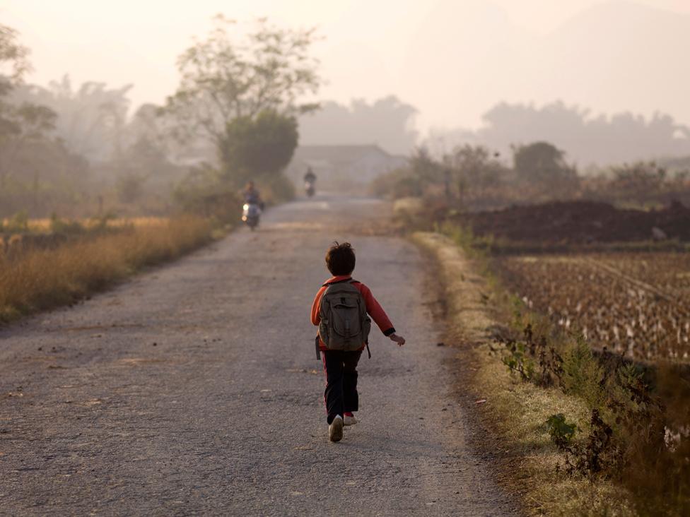 Young Boy Skipping Down A Road In China; Guangxi Zhuang,China