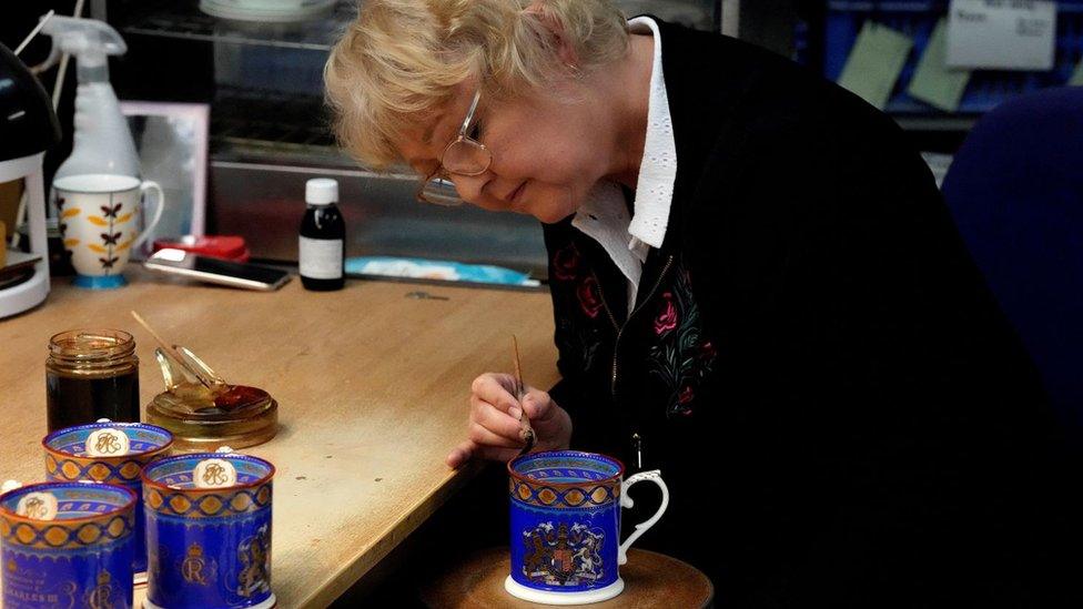 A worker paints the finish on official chinaware in a pottery in Stoke-on-Trent