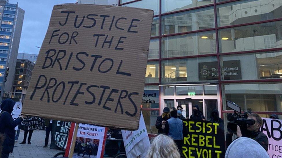 Cardboard sign saying justice for the Bristol protesters