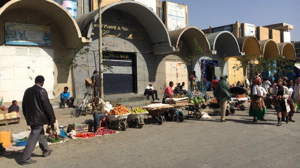 People walking past an open market