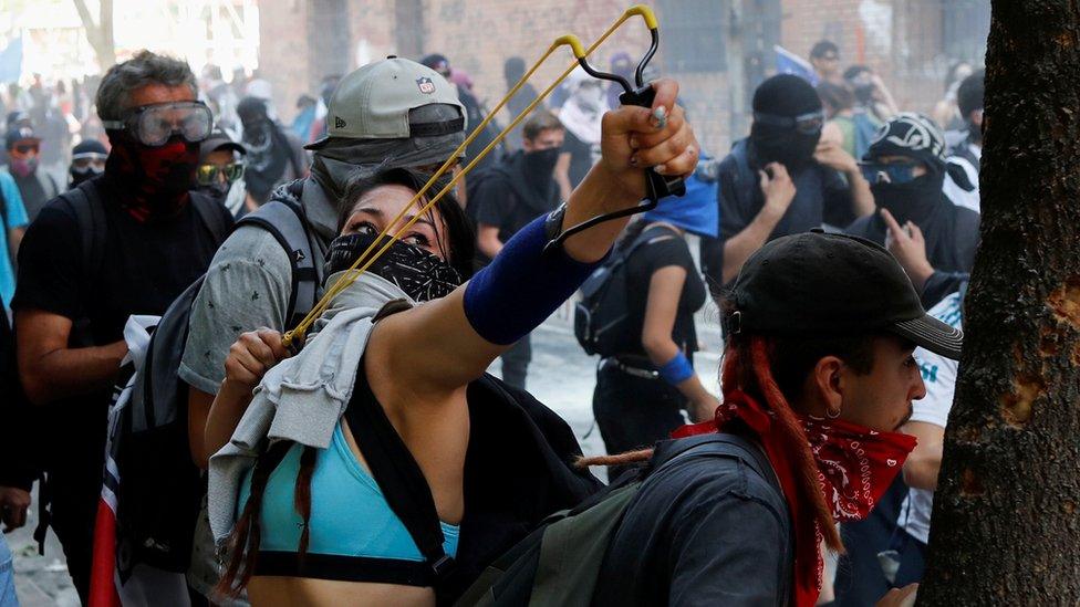 A woman holds a slingshot during a protest