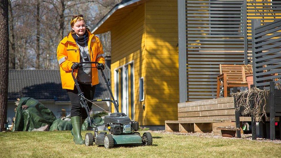 A Posti photo showing a female postal worker mowing a lawn