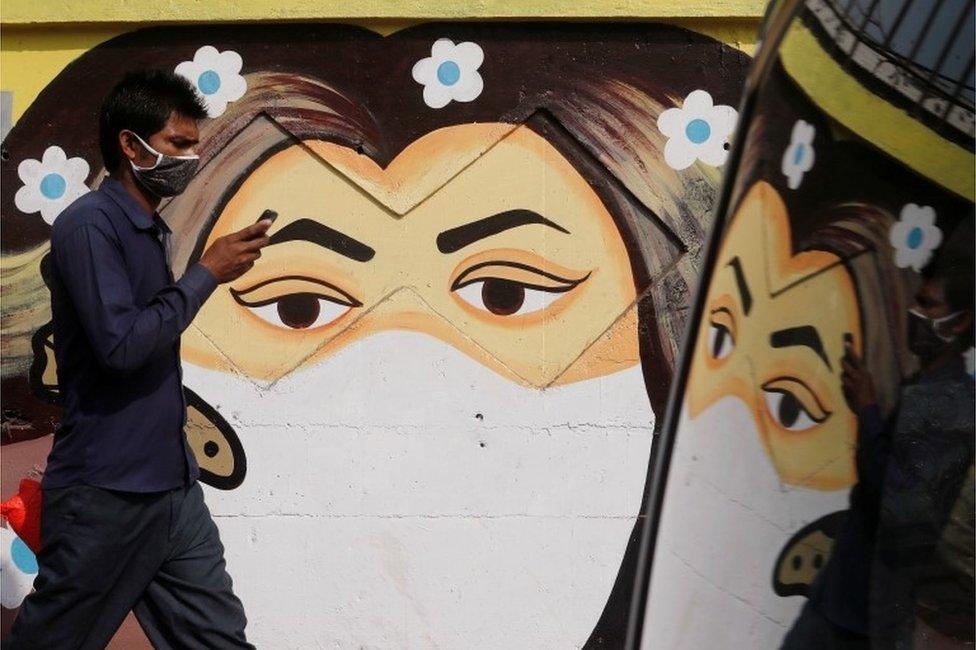 A man walks past a graffiti of a girl wearing a protective mask amidst the spread of the coronavirus disease (COVID-19) on a street in Navi Mumbai, India January 21, 2021.