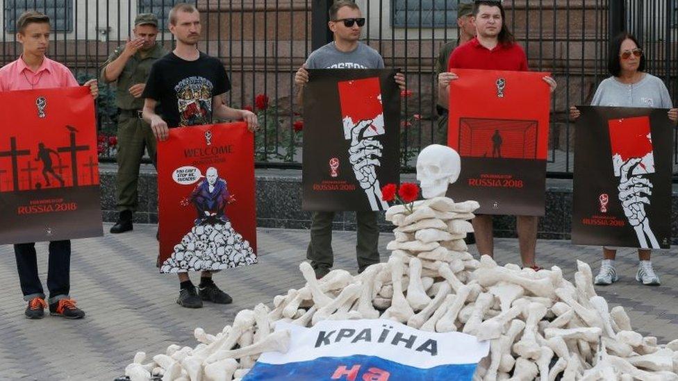 Protesters in front of the Russian embassy in Kiev hold posters by artist Andriy Yermolenko, urging for the boycott of the World Cup in Russia. Photo: 14 June 2018