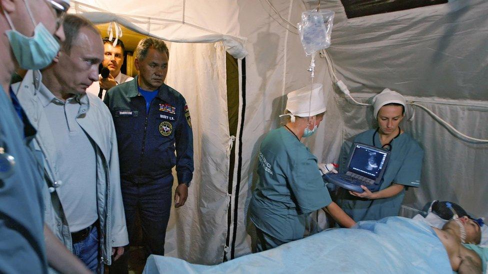 Vladimir Putin (2nd L) looks at a man injured during fighting in South Ossetia during a visit to a field hospital in Vladikavkaz, the provincial capital of the region of North Ossetia