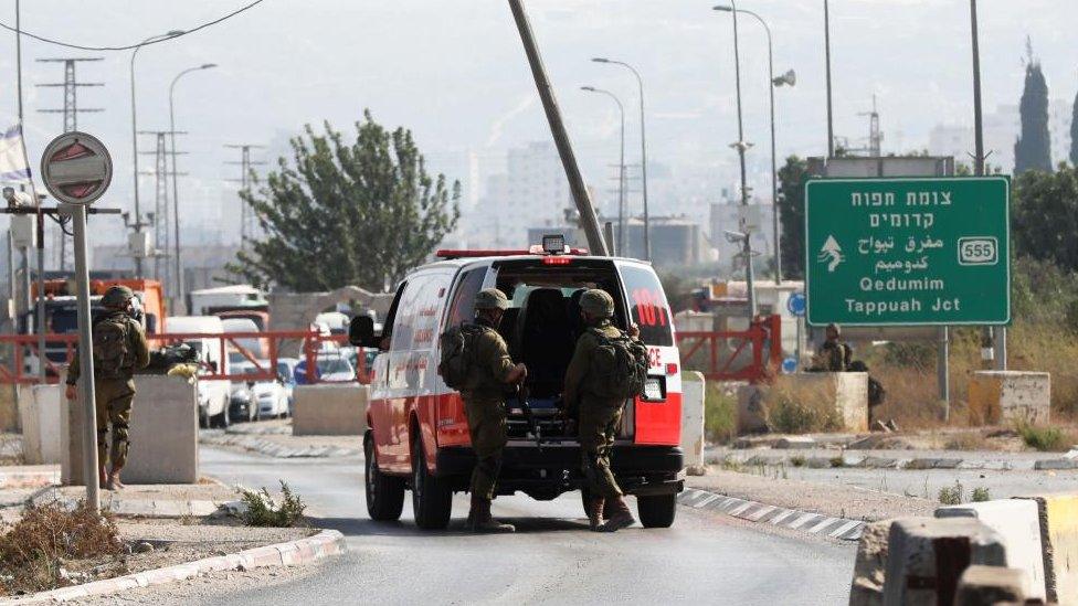 Israeli soldiers stand by an ambulance