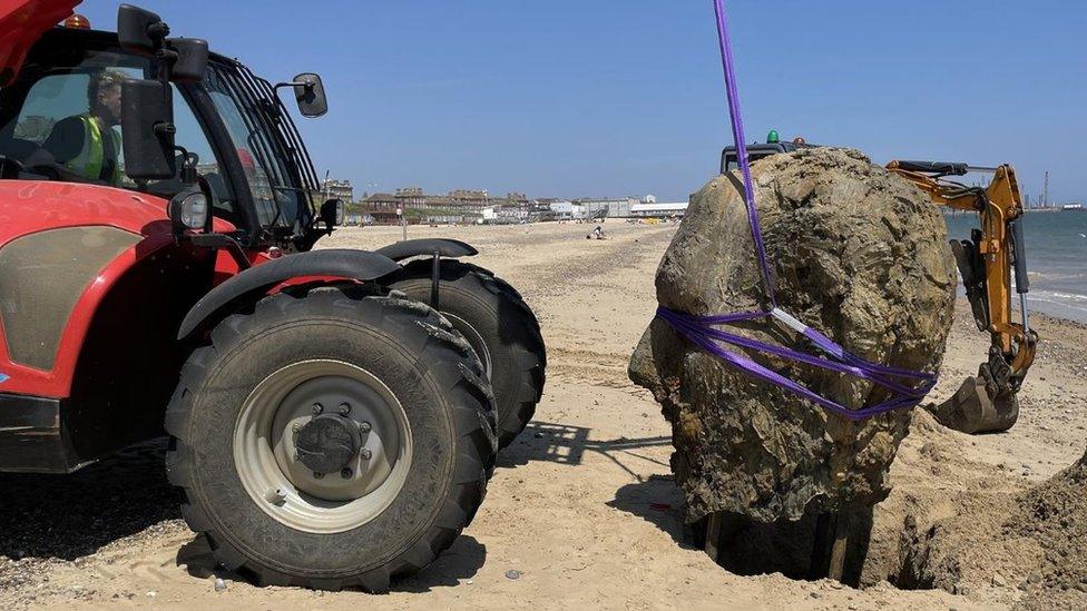 Tractor lifting sculpture into place on a Lowestoft beach