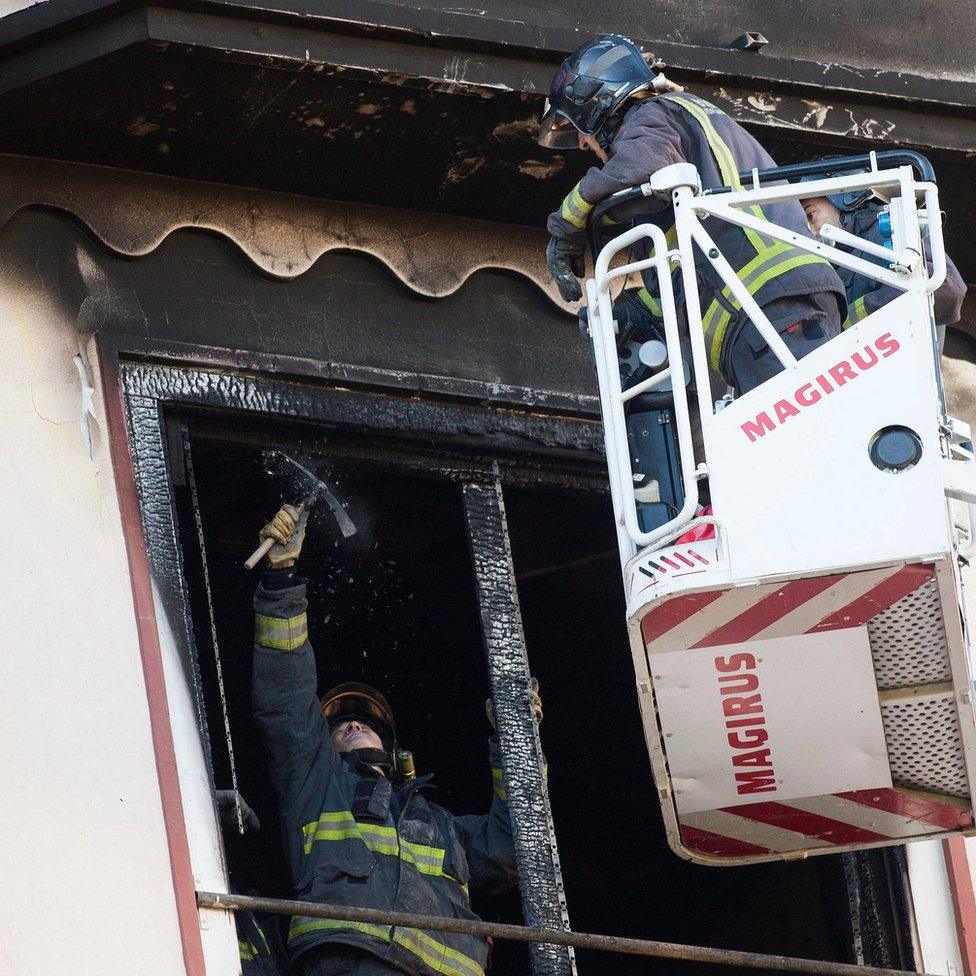 Firefighters inspect a charred window of a building where a fire claimed the life of a 12-year-old girl in Zaragoza, Spain, on 6 November 2016