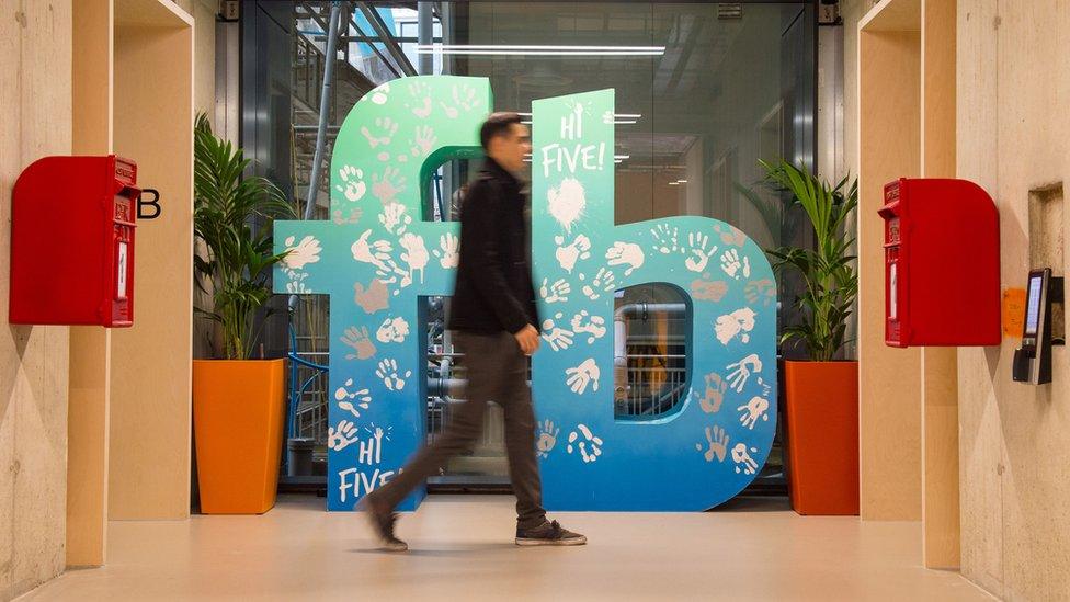 A man walks past a Facebook logo at Facebook's new Frank Gehry-designed headquarters at Rathbone Place in London.