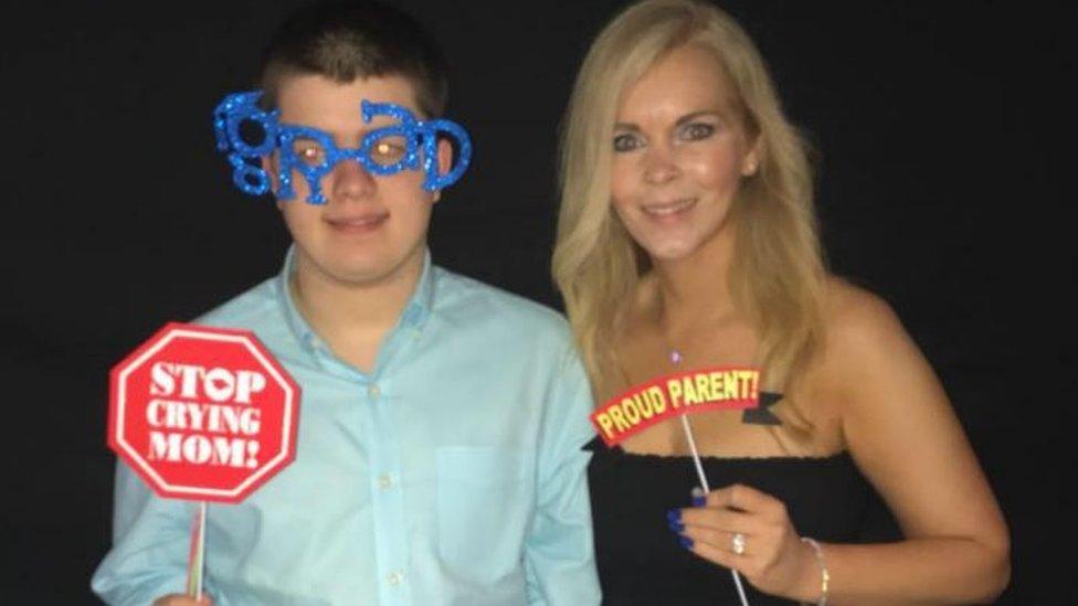 Jack holds up a sign saying 'Stop crying mom!' and Michelle's sign says 'Proud parent'