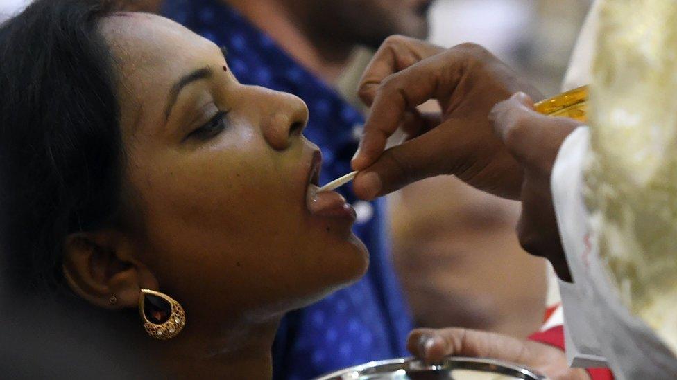 A Sri Lankan Christian devotee receives holy communion during the Christmas Mass in Colombo on 25 December, 2016