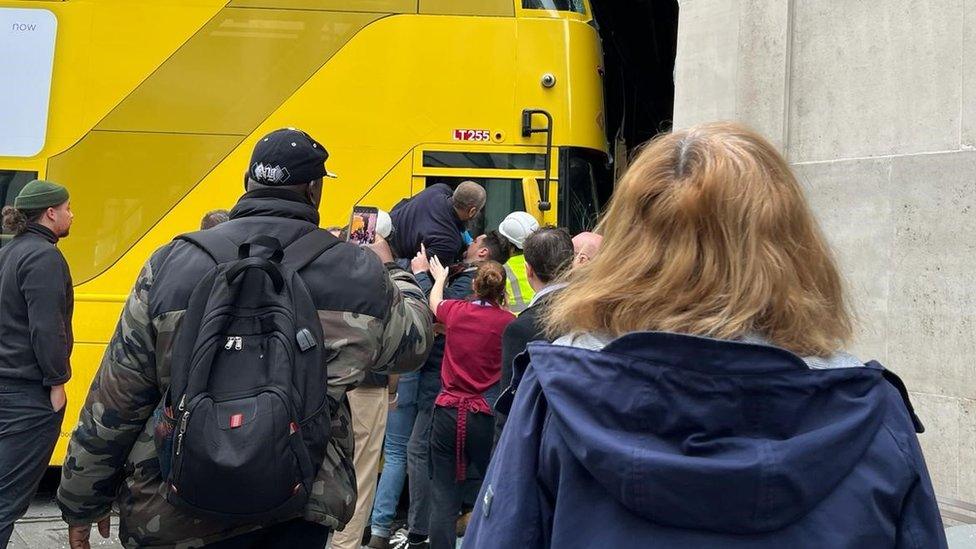 Image of the bus driver being pulled out of the bus by members of the public through the driver's window