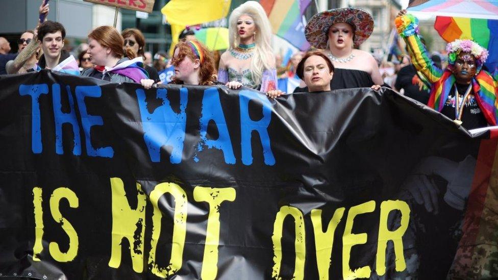 People hold a banner saying "the war is not over"