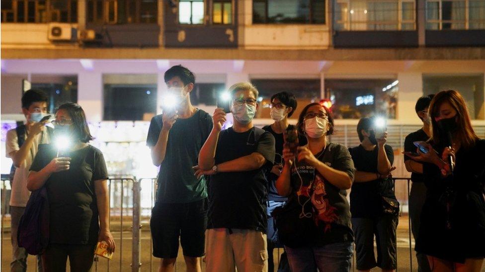 People gather with their phone lights on near Victoria Park, June 2021