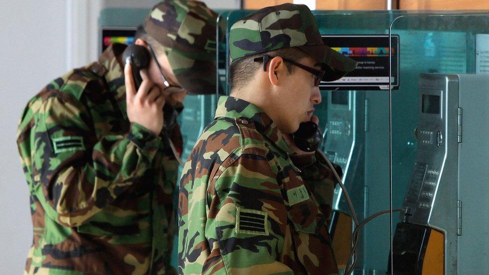 South Korean soldiers use payphones