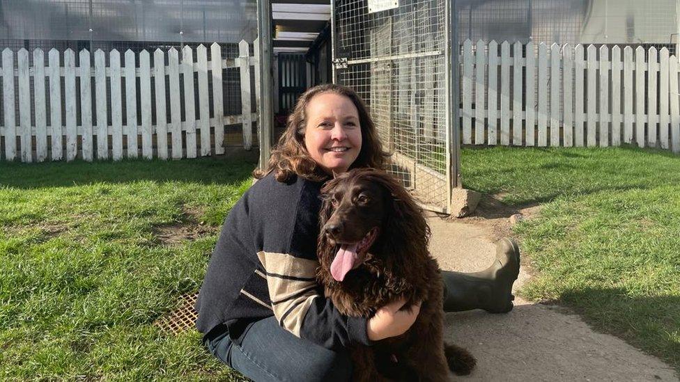 Andrea Burley and her dog Baxter in front of the kennel