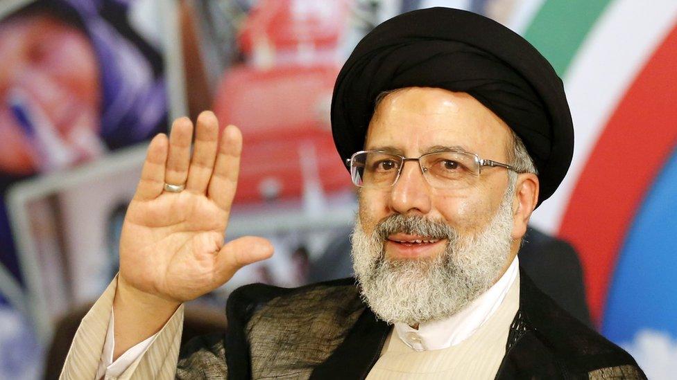 Ebrahim Raisi with hand raised in greeting