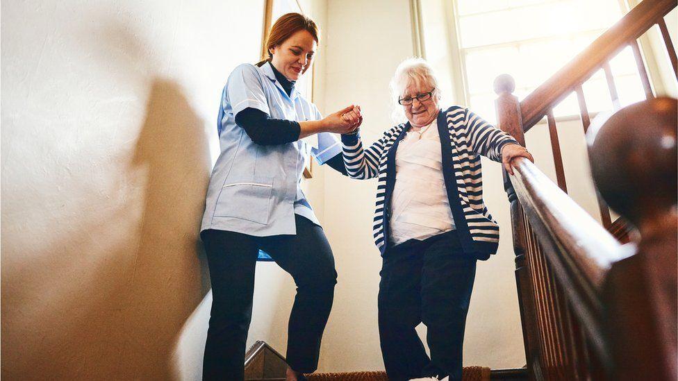 Care worker helping woman down the stairs