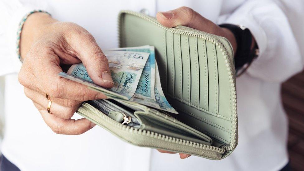 Woman looking at money in her purse