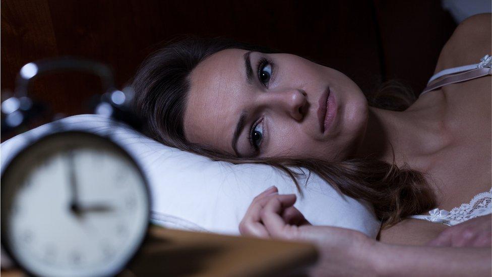 woman in bed with alarm clock