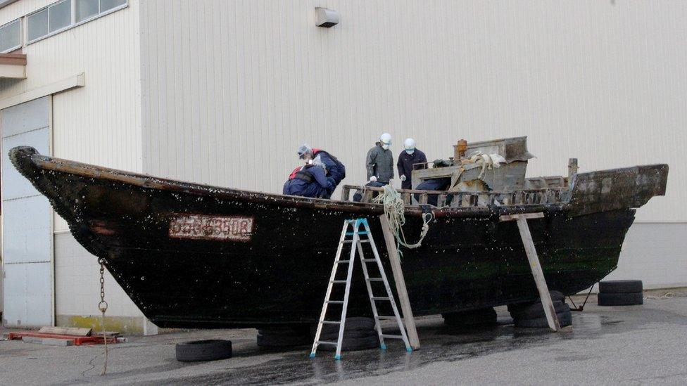 Coast guard officials investigating a wooden boat at the Fukui port in Sakai city in Fukui prefecture, western Japan