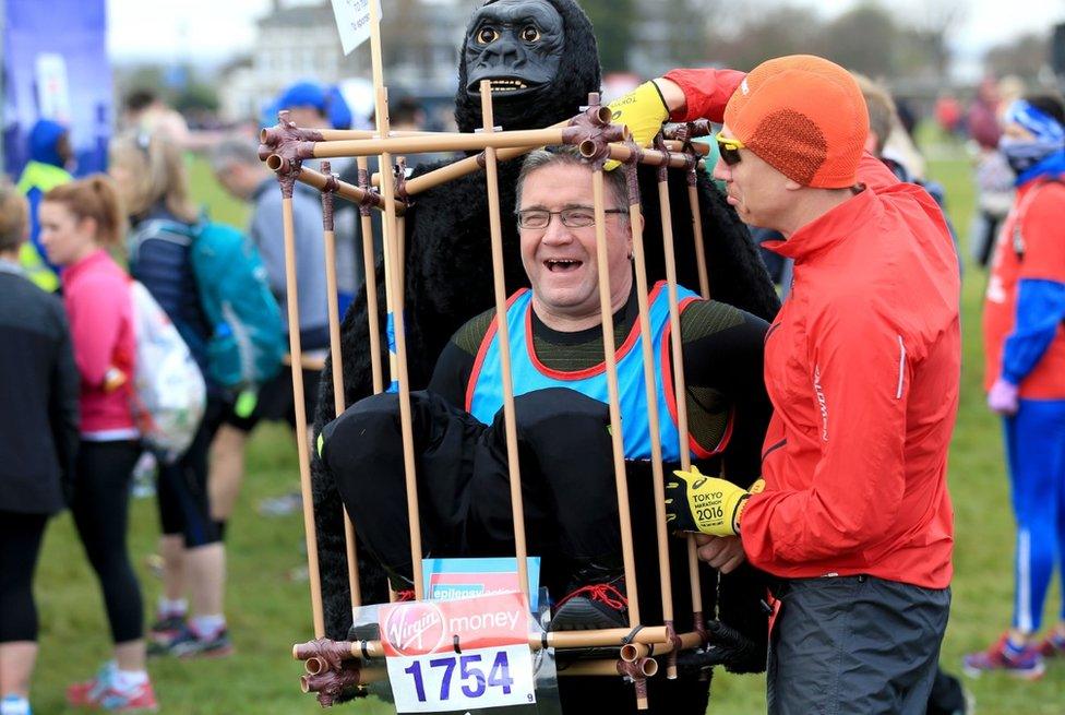 A runner helps a man in fancy dress to adjust his gorilla costume