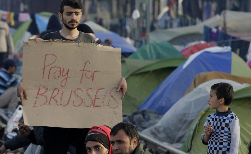 Migrant holds up sign in support of victims of attacks in Brussels at refugee camp on Greek-Macedonian border, in Idomeni, Greece